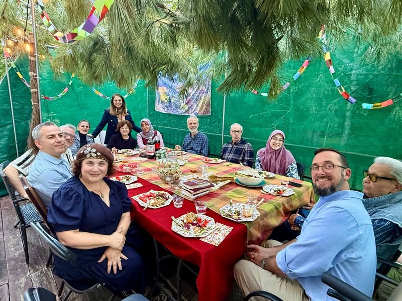 Guests gather in a sukkah for a Qur'an and Torah scripture conversation hosted by Atlantic Institute during Sukkot